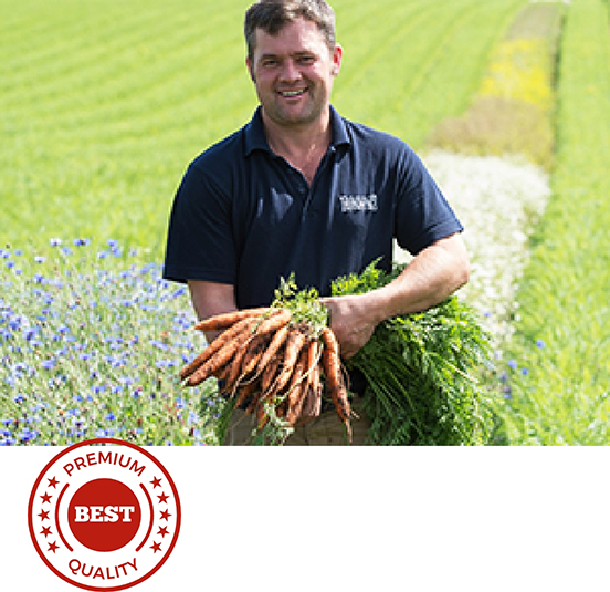 Man holding vegetables in field.